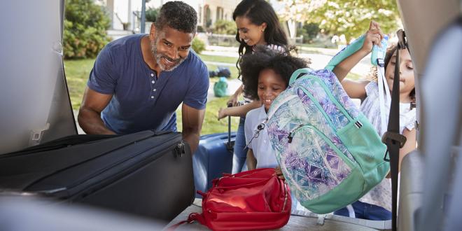 a family packing the car for a vacation, including a red bag