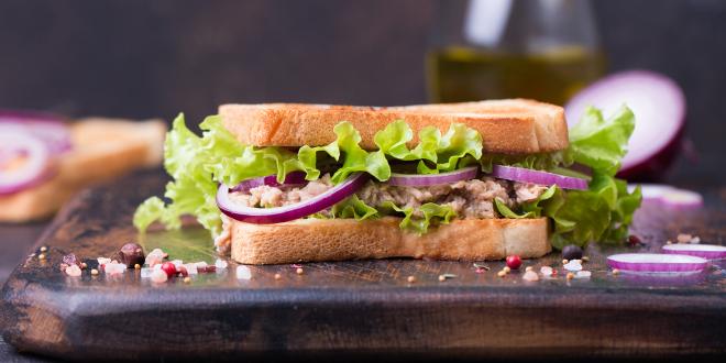 a tuna salad sandwich with red onion and lettuce